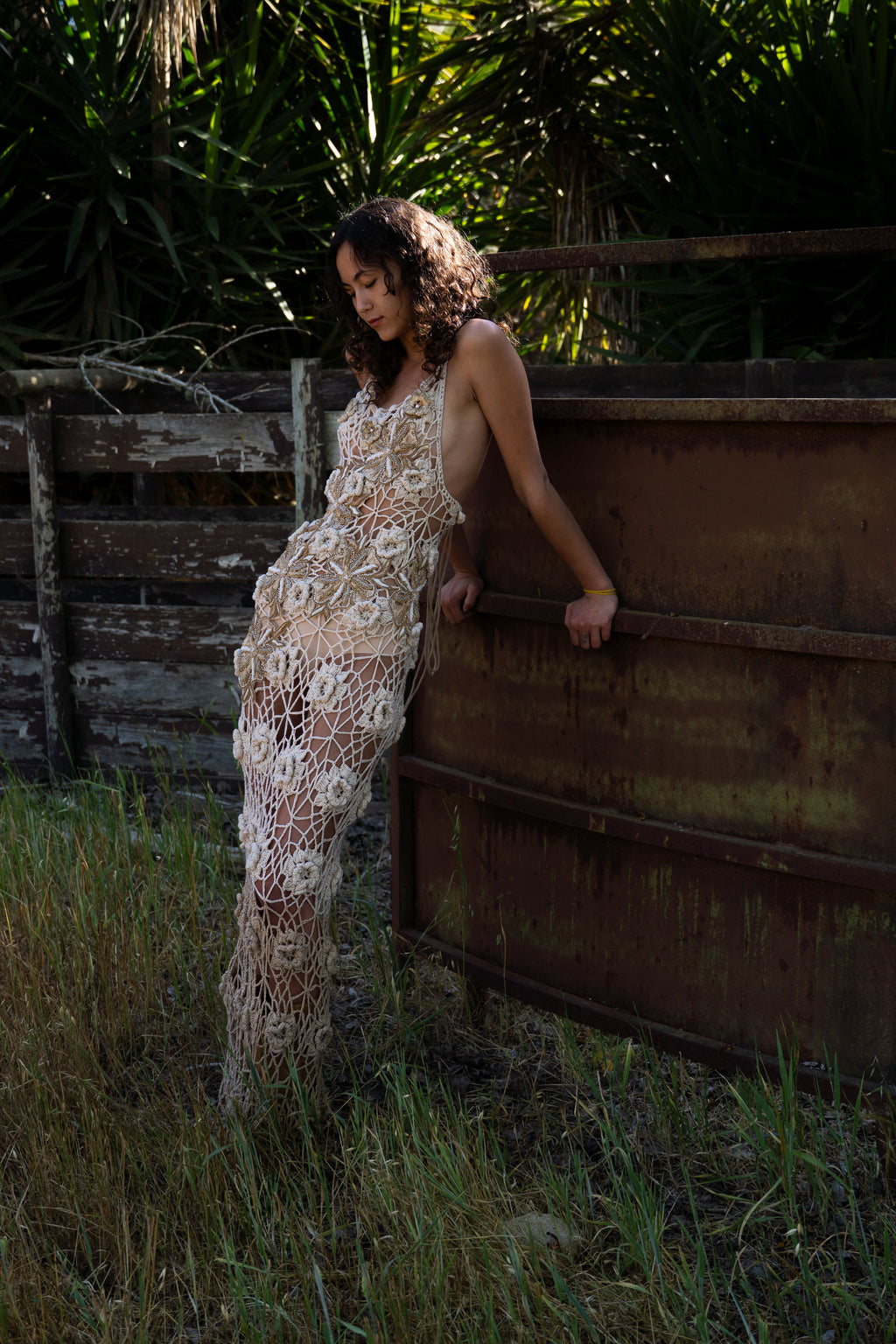 La Sirena hand-crocheted maxi dress with 3D floral embellishments in honey, gold, and cream tones, low back design
