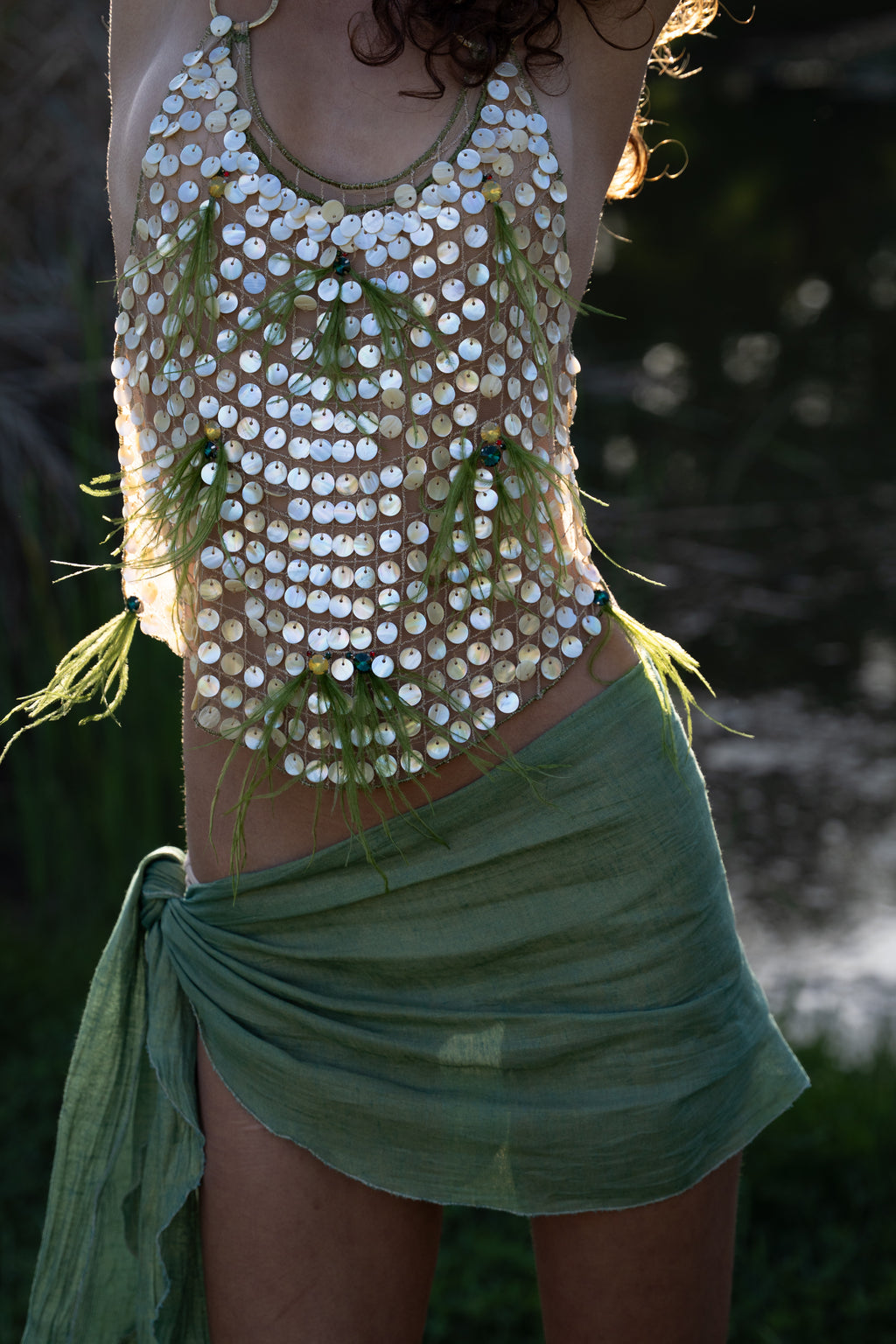 Aura handmade halter top with natural abalone seashell embellishments, sheer nude tulle, light olive ostrich feathers and red and green crystal accents
