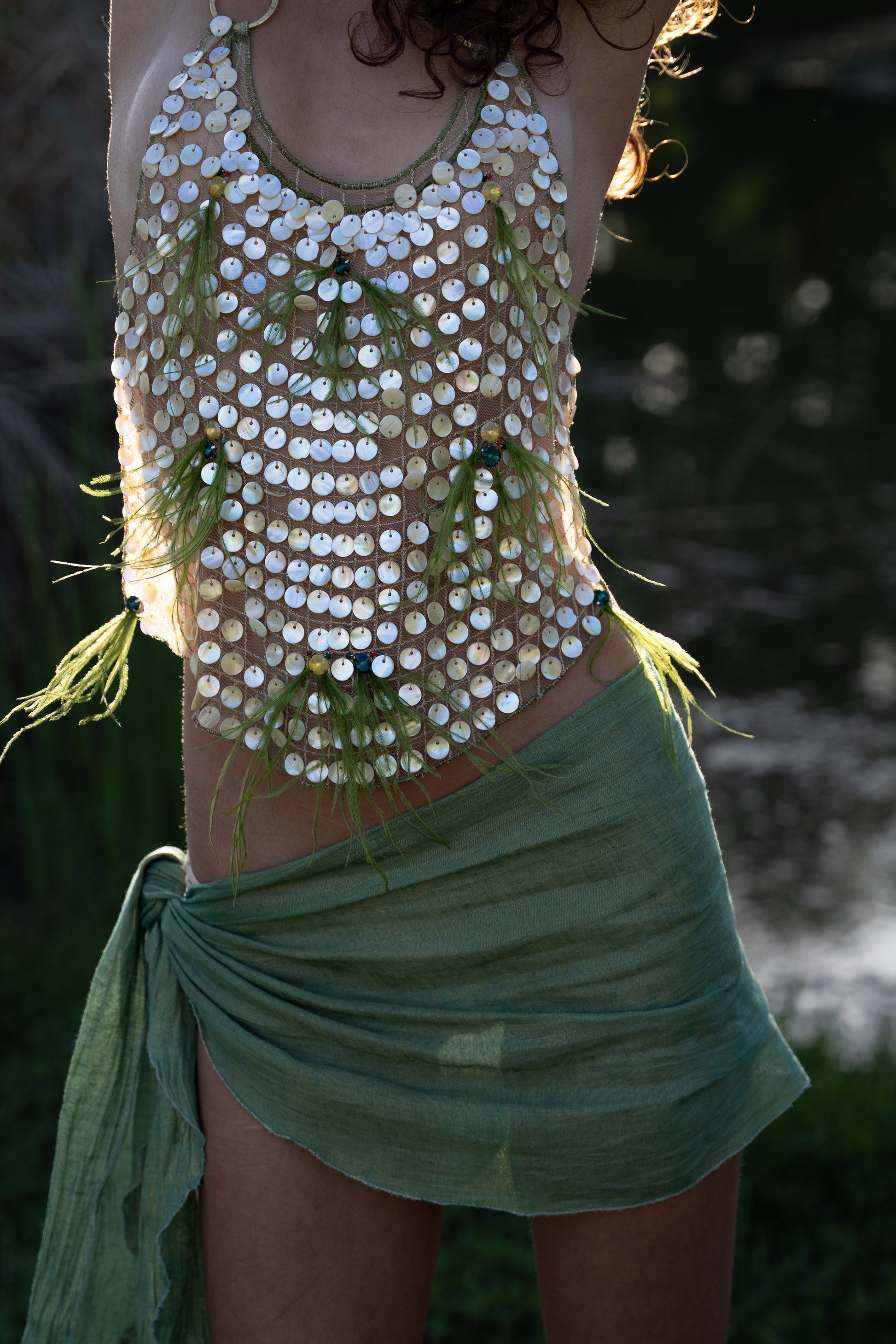 Aura handmade halter top with natural abalone seashell embellishments, sheer nude tulle, light olive ostrich feathers and red and green crystal accents
