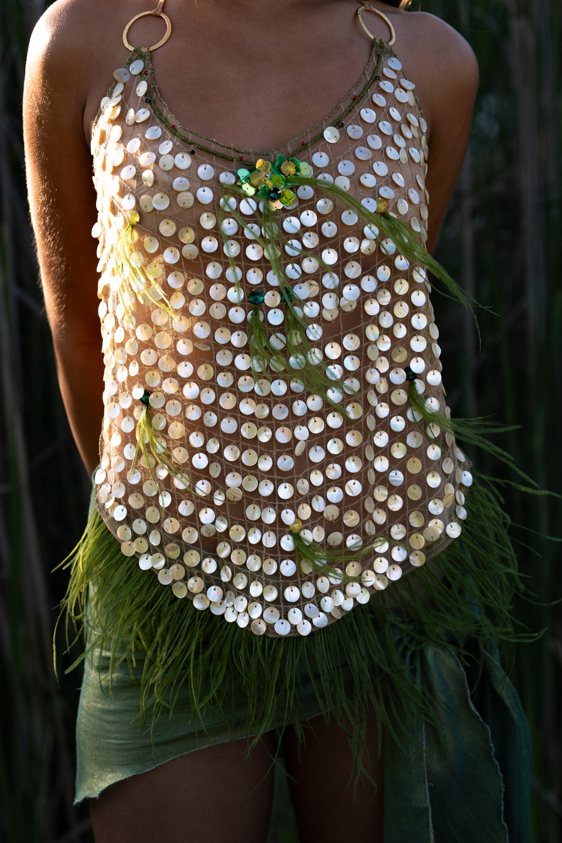 Aura handmade halter top with natural abalone seashell embellishments, sheer nude tulle, light olive ostrich feathers and red and green crystal accents
