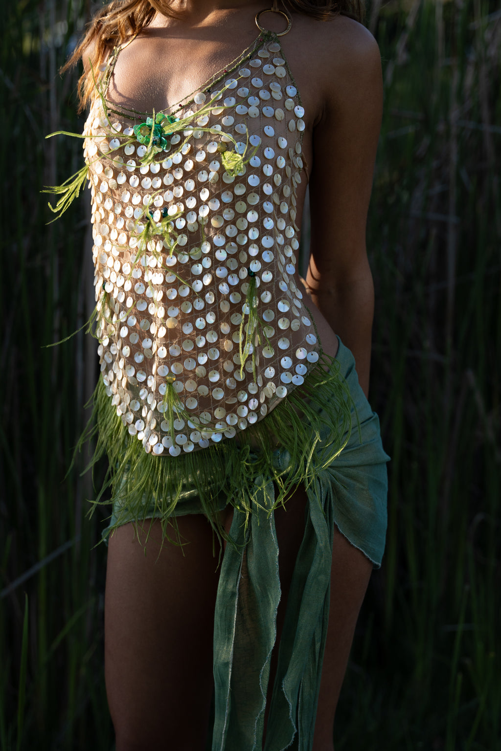 Aura handmade halter top with natural abalone seashell embellishments, sheer nude tulle, light olive ostrich feathers and red and green crystal accents
